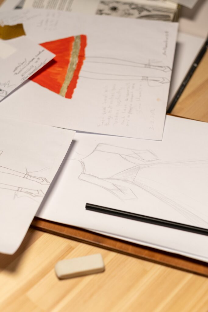 Close-up of fashion sketches on desk with pencil and eraser, highlighting the creative process.